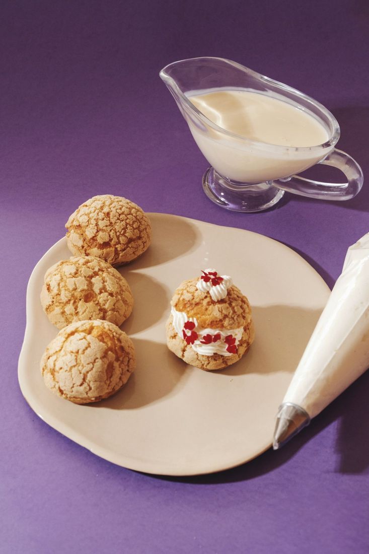 Choux buns on a plate against purple