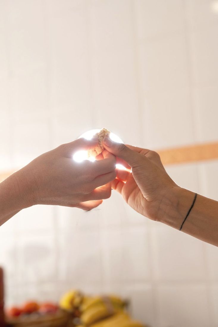 Two hands passing something small in the light